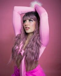 a woman with pink hair posing on a pink background